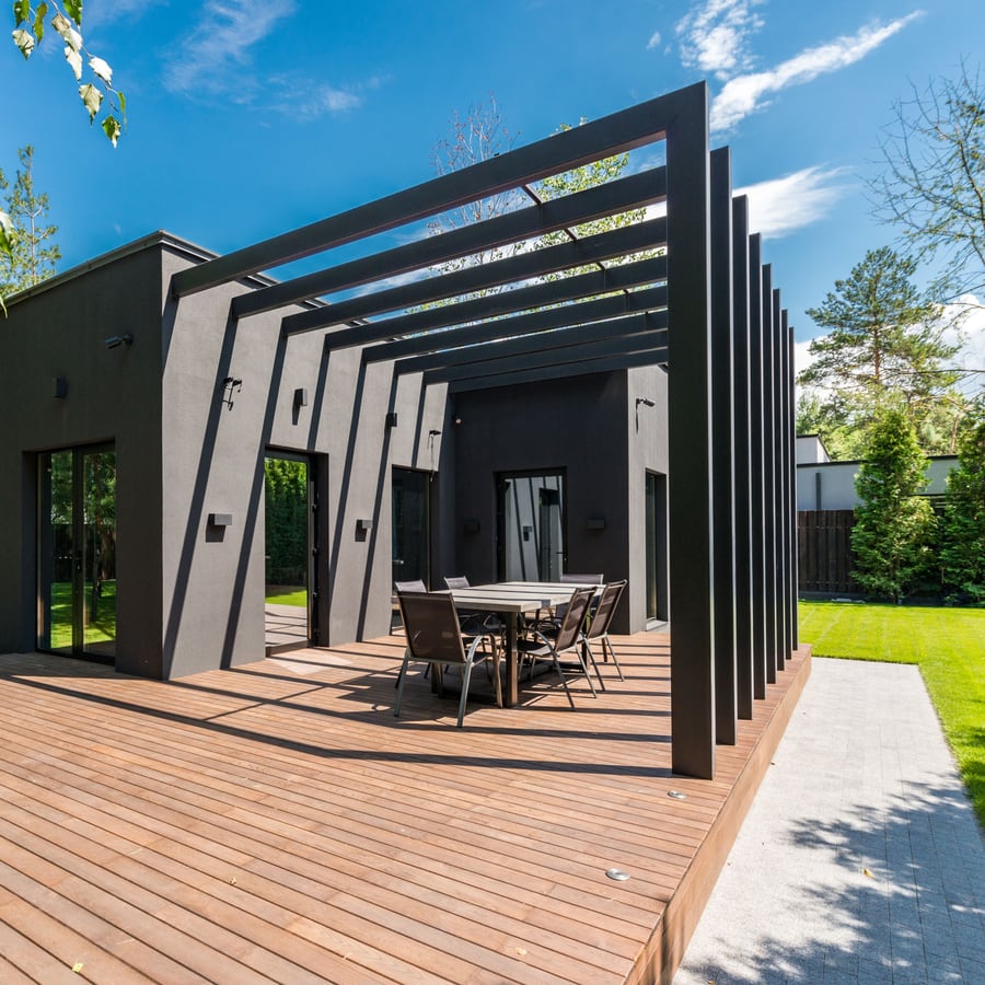 Vom Gärtner angelegte Holzterrasse mit Pergola und Sitzgruppe am Haus