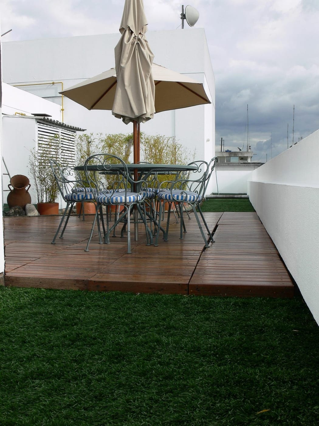 Vom Landschaftsgärtner gebaute Holzterrasse mit Sonnenschirm und Sitzgruppe im Garten