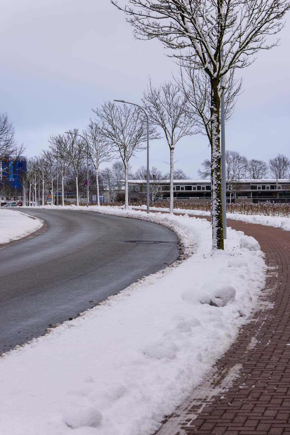 Vom Landschaftsgärtner im Winterdienst geräumte Straße und Gehweg mit aufgeschobenen Schneewällen